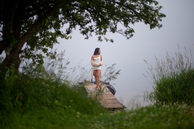 Фото Красивая девушка стоит на пристани у реки