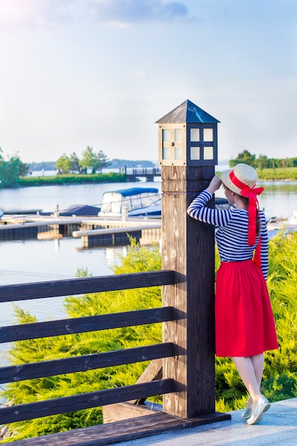 Beautiful girl in a straw hat on the pier near the sea yachts and boats.