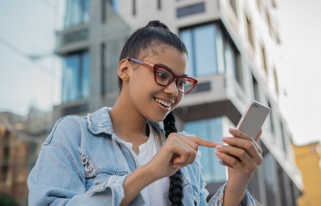 Beautiful girl in stylish eyeglasses reading news online, watching movie