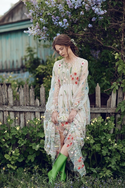 Beautiful girl in a summer dress posing against a background of flowers