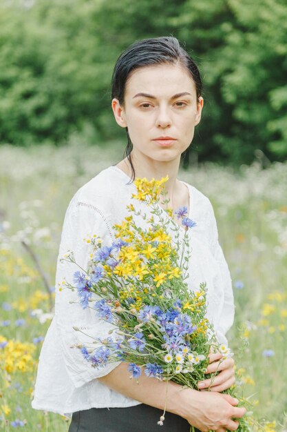 Beautiful girl among the summer field with wildflowers closeup