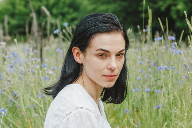 Beautiful girl among the summer field with wildflowers closeup