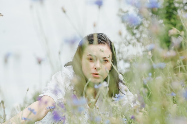 Beautiful girl among the summer field with wildflowers