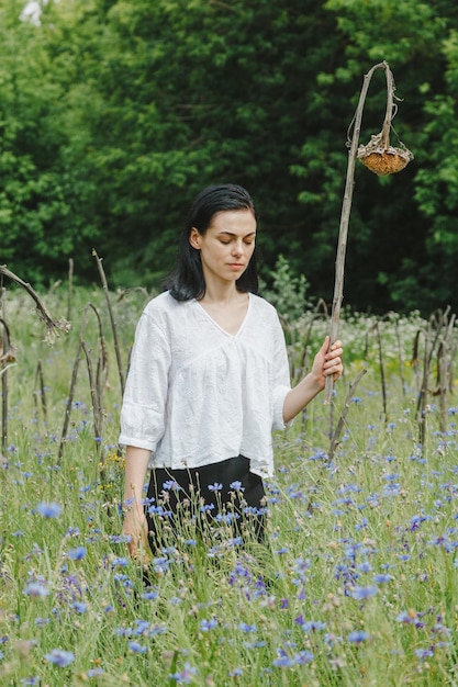 Beautiful girl among the summer field with wildflowers