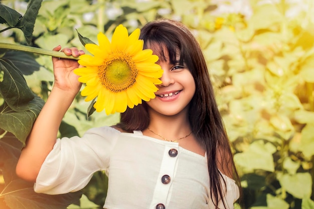 Beautiful girl in a sunflower field, half of her face is covered with sunflowers.