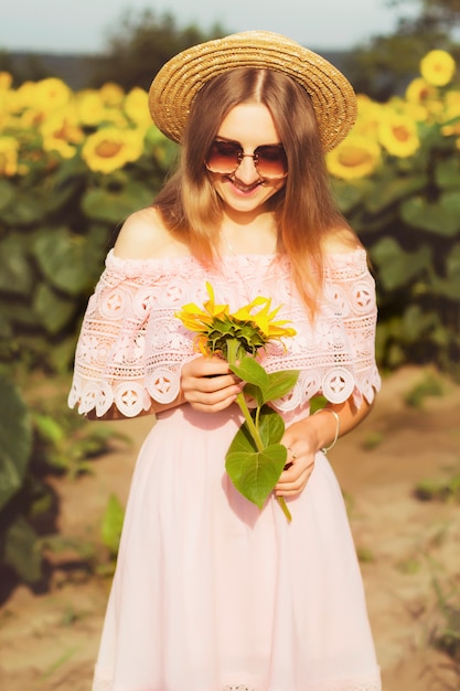 Bella ragazza nei girasoli al tramonto