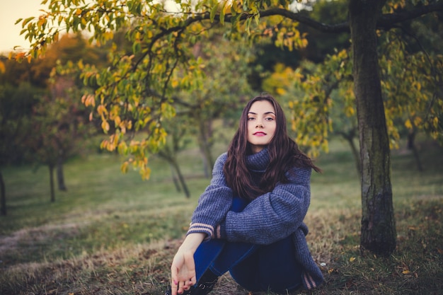 秋の公園でセーターを着た美しい少女