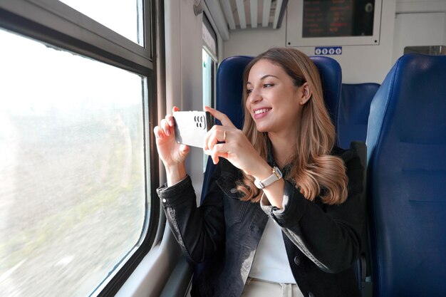 美少女が電車に座ってスマートフォンで風景の写真を撮る