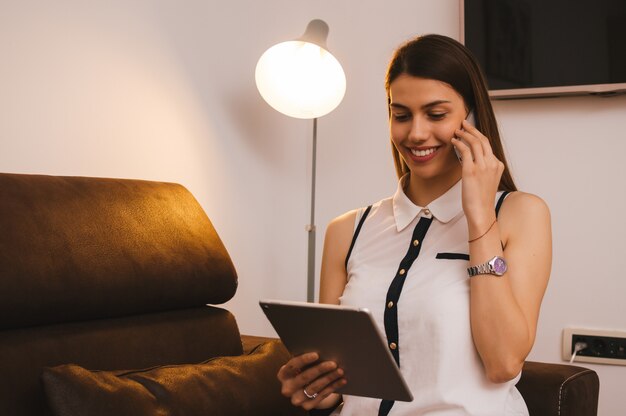 Foto bella ragazza parla al cellulare mentre si utilizza il tablet pc