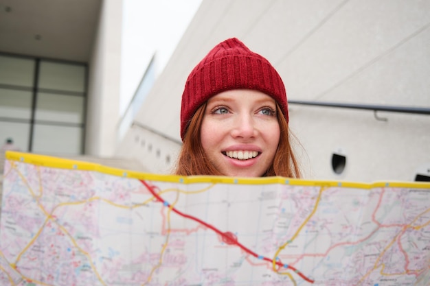 Photo beautiful girl tourist sits on stairs with city map plans her journey looks for direction while trav