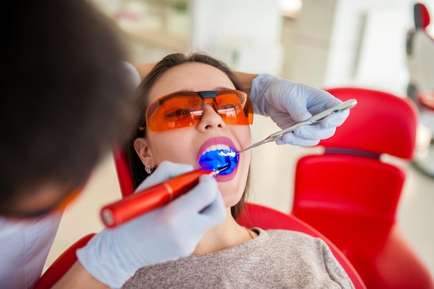 Beautiful girl treats teeth in dentistry