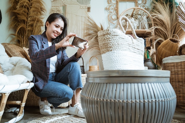 Photo beautiful girl using a handphone when take a woven bag shot in a handicraft shop