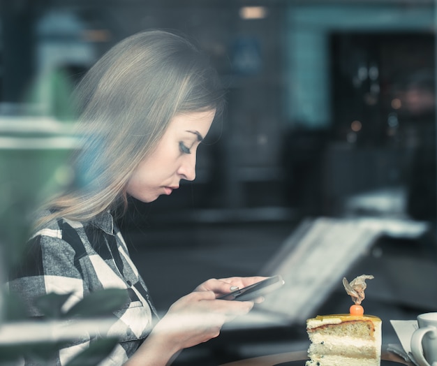 カフェで携帯電話を使用して美しい少女