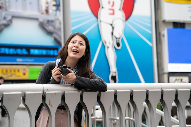 beautiful girl visitor shooting photos on the bridge.  by the background of Dontonbori.