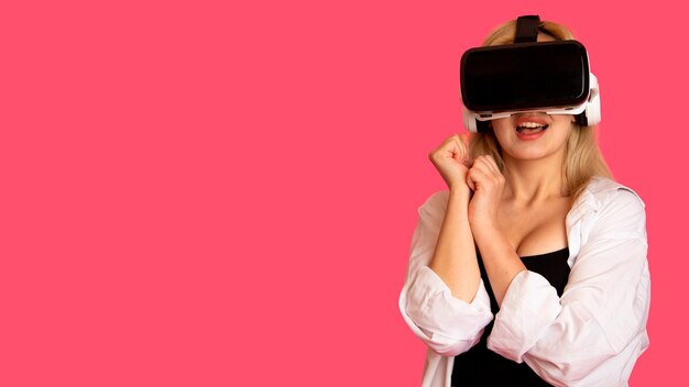 Foto bella ragazza con gli occhiali vr su uno sfondo rosa nella realtà virtuale