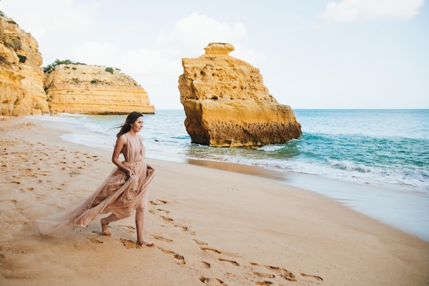 Красивая девушка гуляет по пляжу на закате, концепция свободы