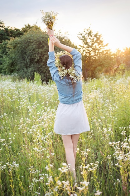 Beautiful girl walking on field on summer with wildflowers
