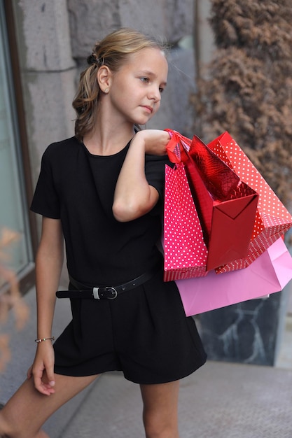 Beautiful girl walking with colored bags in the city