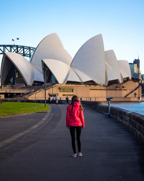 beautiful girl walks by famous sydney opera house at sunrise, sunrise over sydney opera house, aus