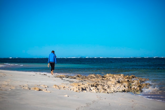 beautiful girl walks on coral bay beach overlooking ningaloo reef in the morning