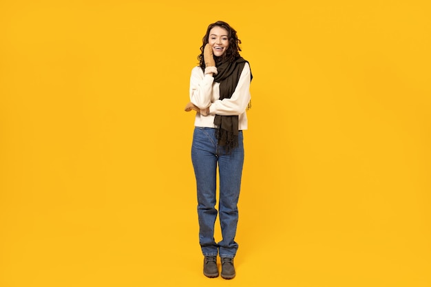 Beautiful girl in warm winter clothes on a yellow background
