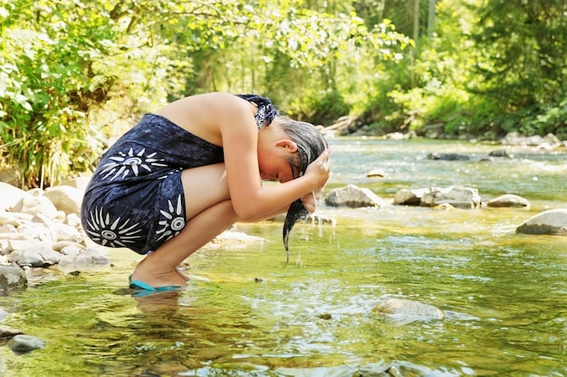 Beautiful girl washes head in the mountain stream