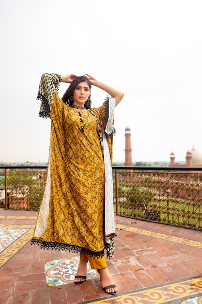 Beautiful Girl Wearing Gold Floral Dress Posing on Roof Top for Fashion Shoot