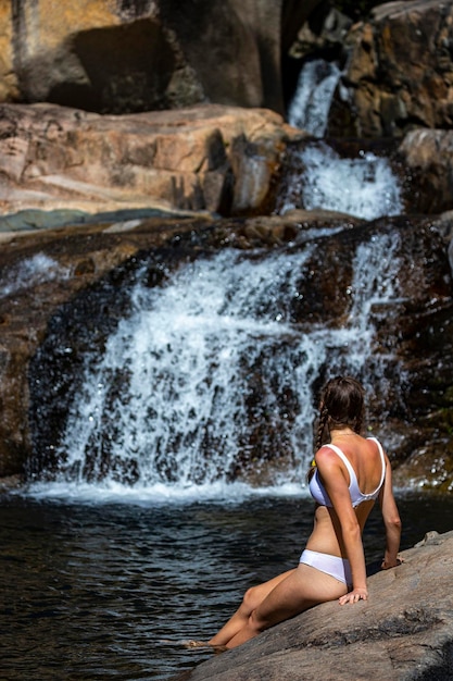 a beautiful girl in a white bikini swims in a natural pool in jourama falls, queensland, australia