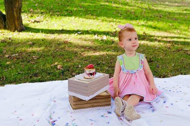 Photo beautiful girl on white blanket with confetti celebrating her birthday with strawberry cake