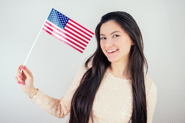 Beautiful girl in a white blouse holding an American flag on a white background The concept of America's Independence Day