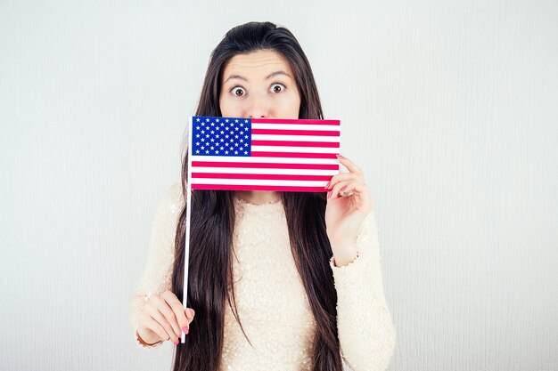 Beautiful girl in a white blouse holding an American flag on a white background Concept July 4 Independence Day of America