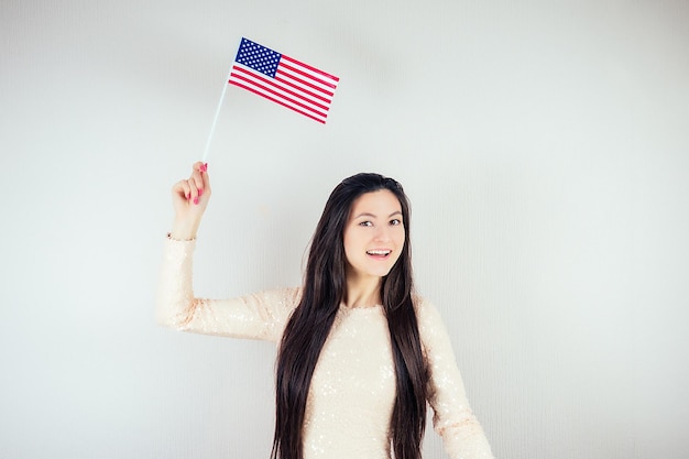 Beautiful girl in a white blouse holding an American flag on a white background Concept July 4 Independence Day of America