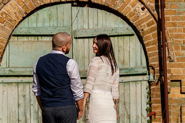 beautiful girl in a white dress and a guy on the background of a brick wall with an old gate closeup