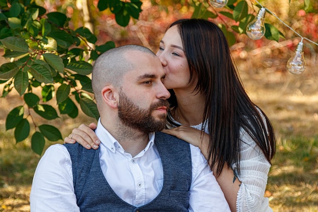 Beautiful girl in a white dress and a guy lie in a clearing a picnic