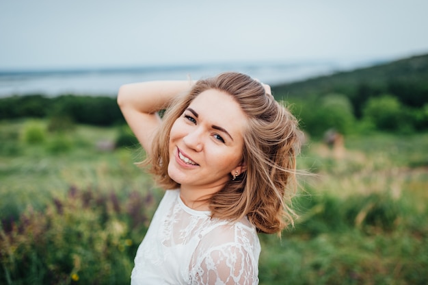 La bella ragazza in vestito bianco si trova in erba verde