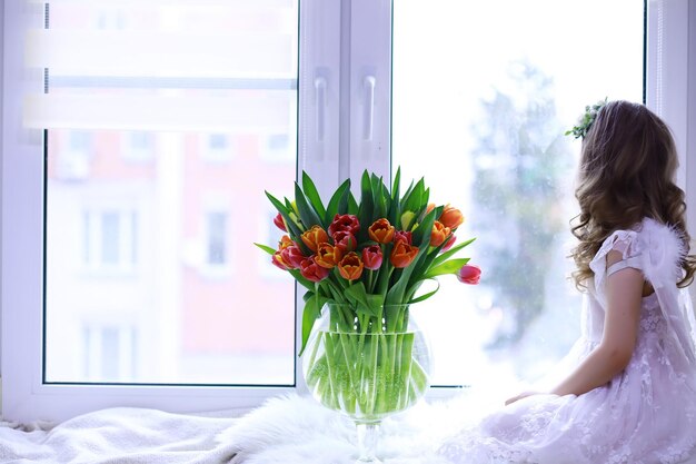 Beautiful girl in white dresses with a magnificent bouquet of the first tulips. International Women's Day. Girl with tulips.