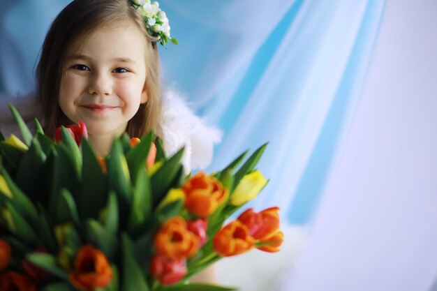 Beautiful girl in white dresses with a magnificent bouquet of the first tulips. International Women's Day. Girl with tulips.