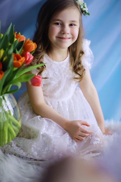 Beautiful girl in white dresses with a magnificent bouquet of the first tulips. International Women's Day. Girl with tulips.