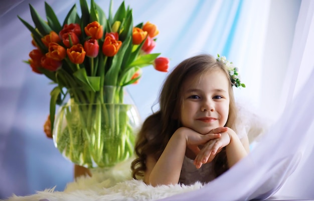 Beautiful girl in white dresses with a magnificent bouquet of the first tulips International Women's Day Girl with tulips