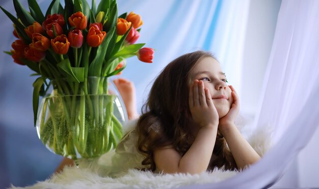 Beautiful girl in white dresses with a magnificent bouquet of the first tulips International Women's Day Girl with tulips