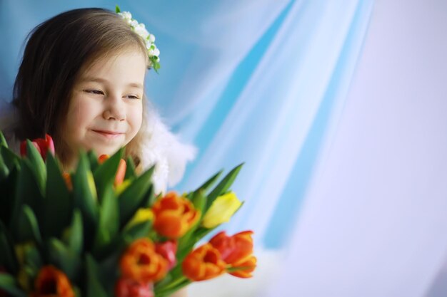 첫 번째 튤립의 장엄한 꽃다발과 함께 하얀 드레스를 입은 아름다운 소녀 국제 여성의 날 튤립을 든 소녀