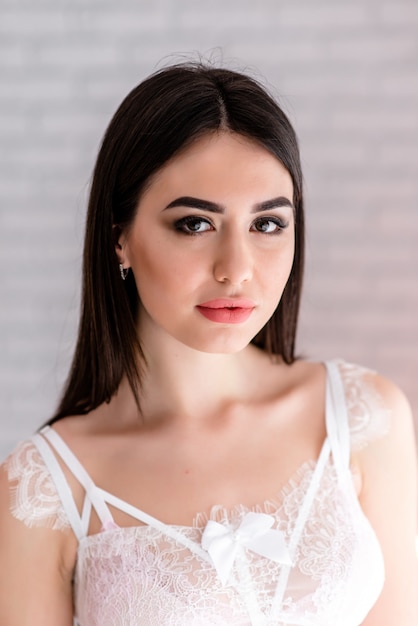 Beautiful girl in white lace boudoir dress on the background colors decor with big window