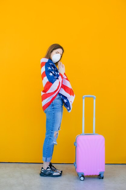 Beautiful girl in a white summer dress with a suitcase Medical mask on the face