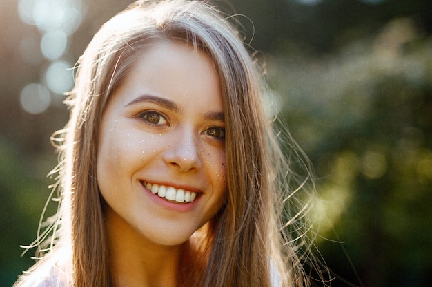 Foto una bella ragazza in una maglietta bianca sorride apertamente, ride e guarda la telecamera.