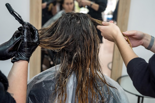 Una bella ragazza che è venuta per la prima volta al salone di bellezza si è sbiancata e si è asciugata i capelli per applicare la vernice concetto di asciugatura dei capelli concetto di salone di bellezza