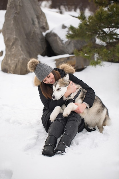 Beautiful girl in winter forest with dog Play with the dog Siberian husky