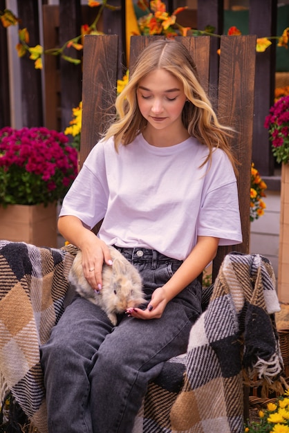 사진 벤치에 집 근처 가을 야외에서 토끼와 함께 아름 다운 소녀