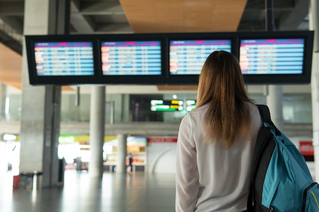 Beautiful girl with backpack stands and choice flight