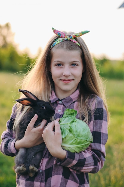 beautiful girl with a black rabbit and cabbage in her hands