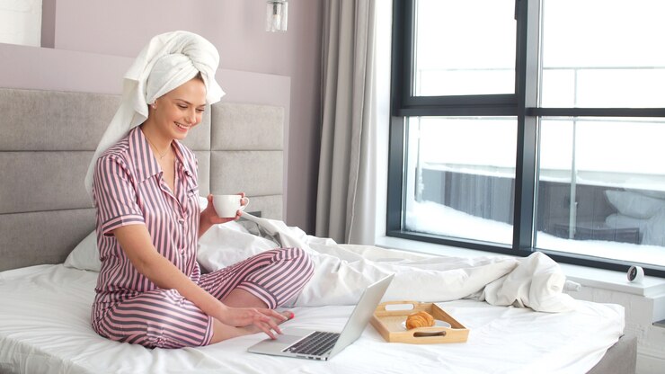 Photo beautiful girl with blue eyes smiles with pleasure working remotely at home on a laptop in quarantine